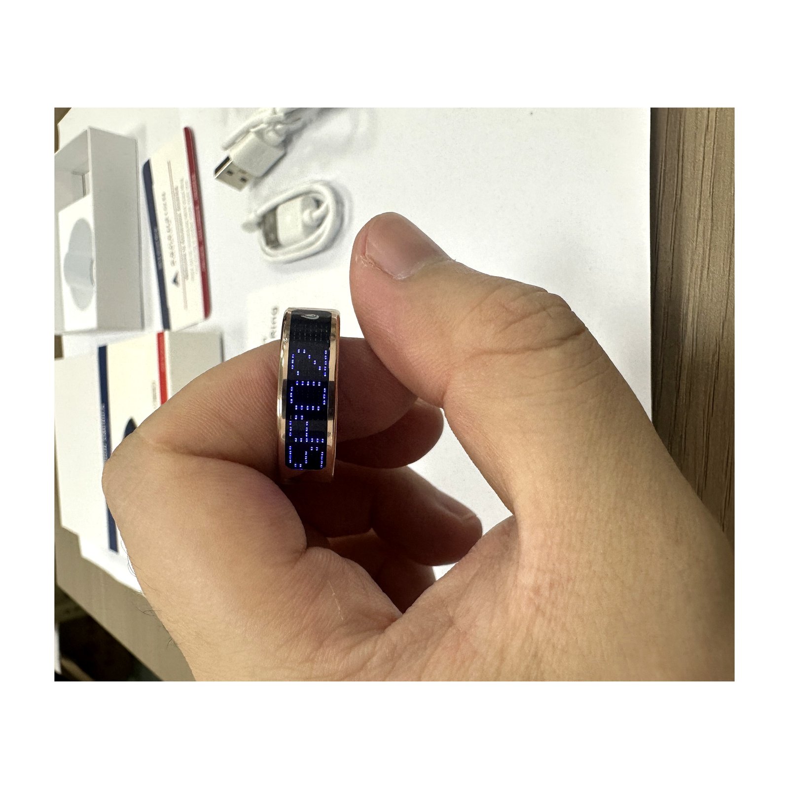 SR16 smart ring in Bright Gold held between fingers showing stainless steel band